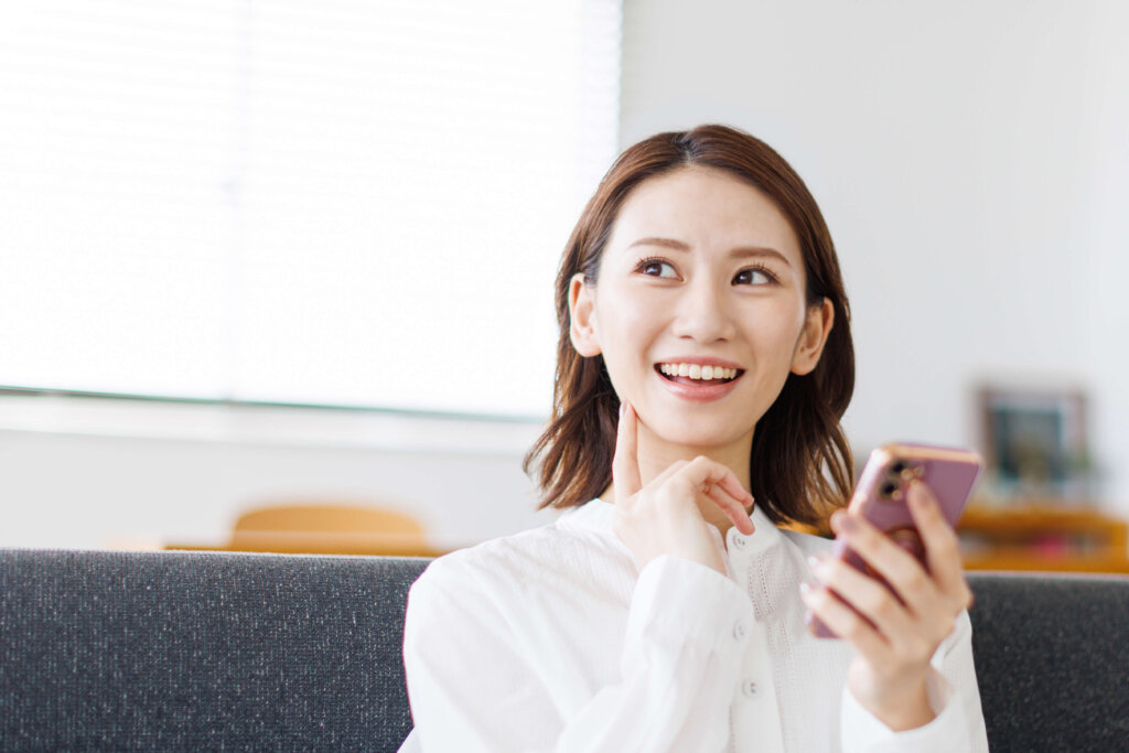 スマホを手に持つ笑顔の女性